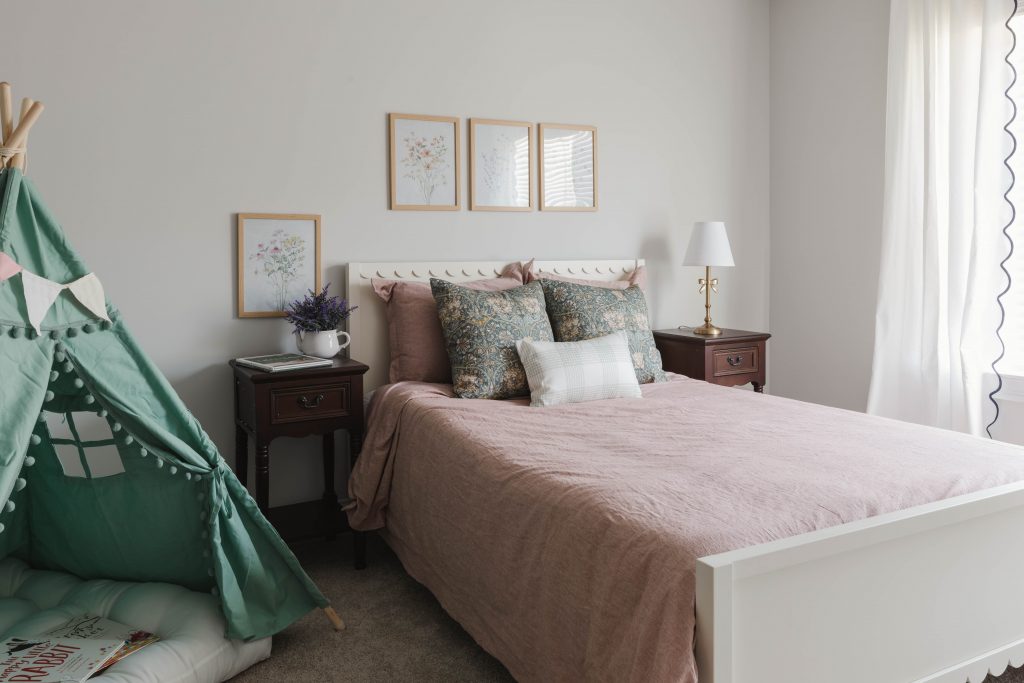 Kids' room with pink bed, flower pictures on the wall, and reading tent