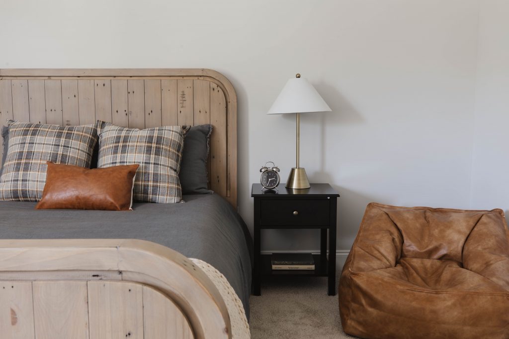 Secondary bedroom with wooden bed frame and leather seat