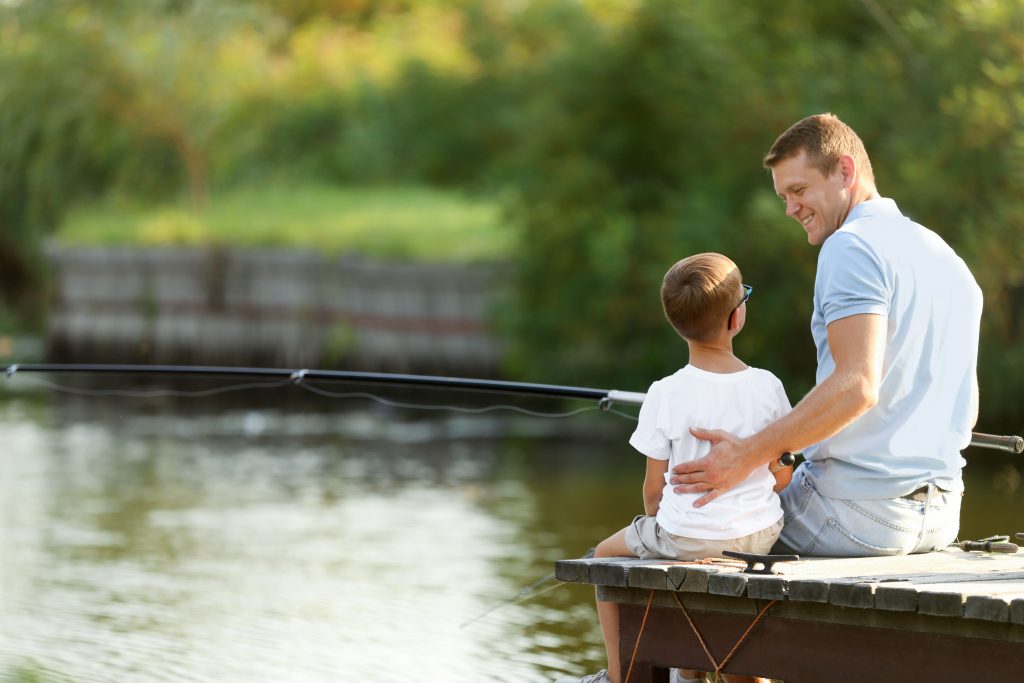 Dad and son fishing together on sunny day