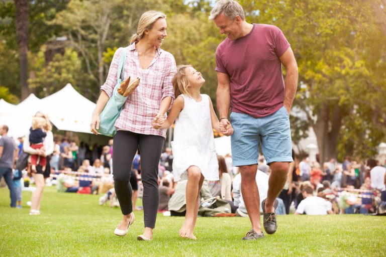 Parents with daughter walking outside during festival ©Monkey Business Images