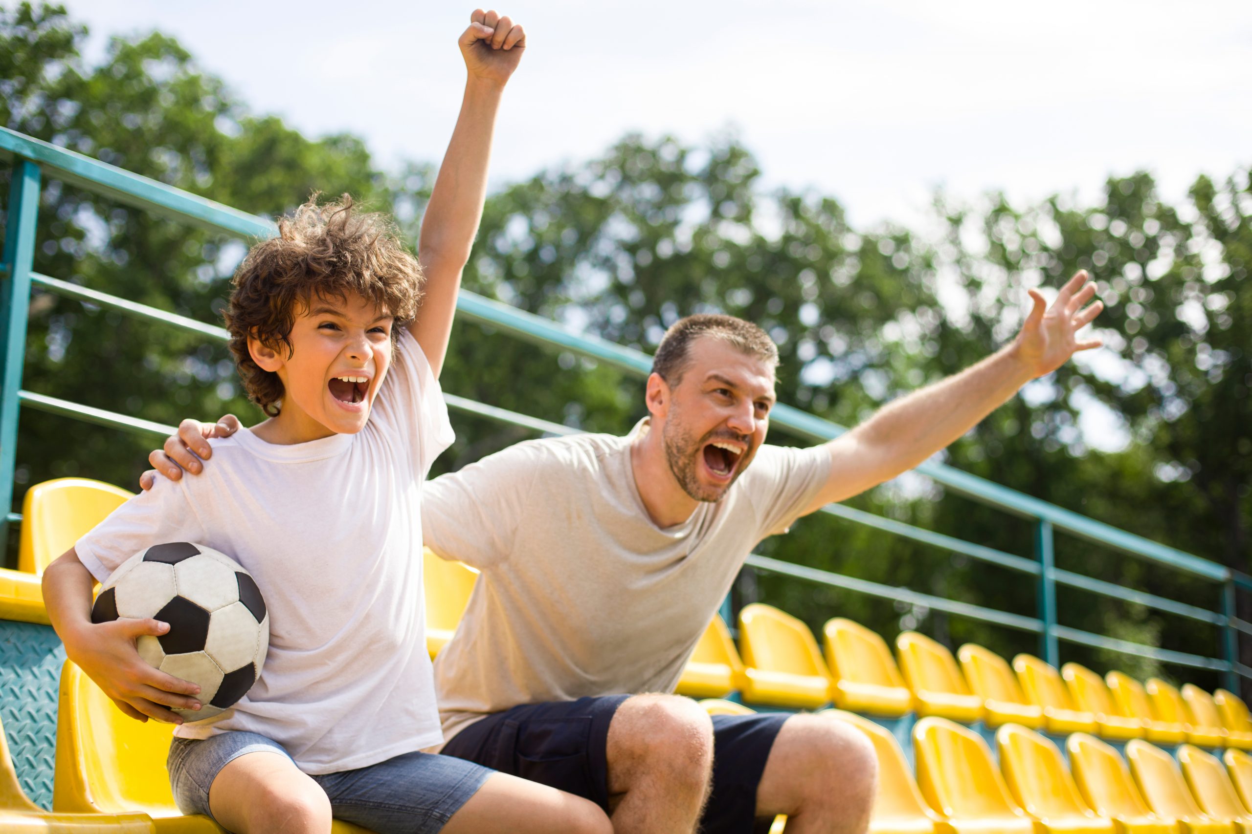 Father and son cheering at soccer game ©Prostock-studio