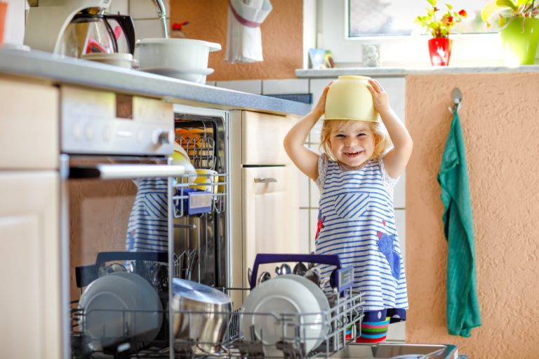 smiling child helping to unload dishwasher and putting bowl on head ©Irina Wilhauk