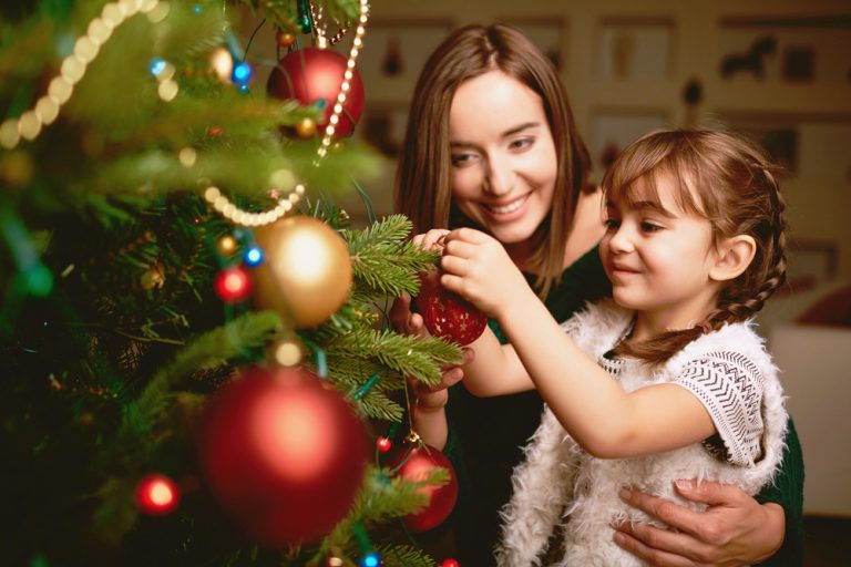 Mom and daughter putting ornaments on the Christmas tree ©Pressmaster