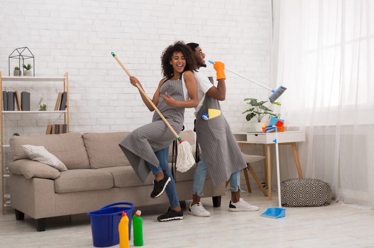 Couple Cleaning Together with a broom and mop pretending to sing