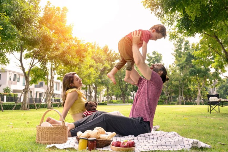Family taking a picnic with the the man picking the child up and having bread, apples, and jam ©Pratchaya.Lee