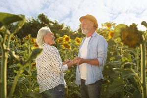 a happy older couple hold hands in a sunflower field ©New Africa