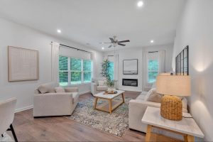 Cozy living room in a farmhouse-style home. There are white couches, a white coffee table, and an electric linear fireplace.