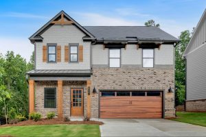 Modern farmhouse-style home in Dallas, GA, with brick accents, a covered front porch, wooden details, and a 2-car garage.