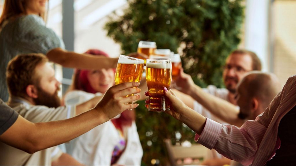 Group of friends cheering with beers at a game day party. ©Anton Vierietin