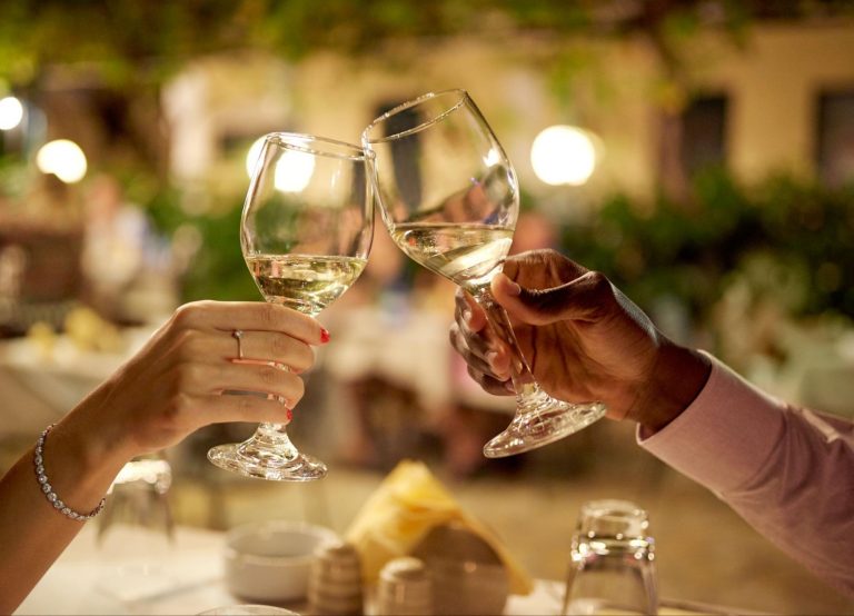 Close-up of a couple's hands clinking glasses of white wine on a romantic date in Adairsville ©PeopleImages