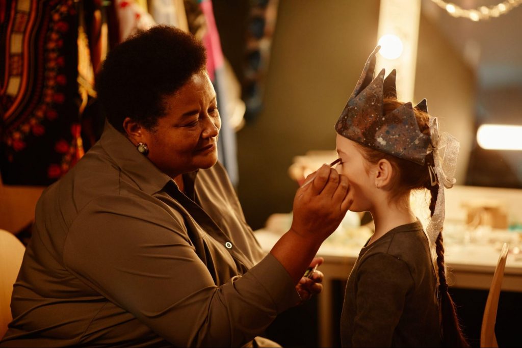  Instructor applying stage makeup to a child wearing a crown at a youth drama camp near Dallas, GA. ©SeventyFour