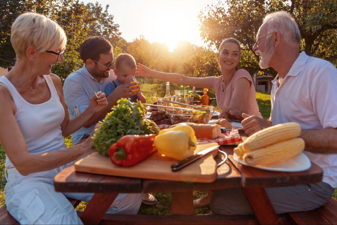 Multigenerational family enjoying an outdoor meal in a sunny backyard in Mableton, GA. ©Ivanko80
