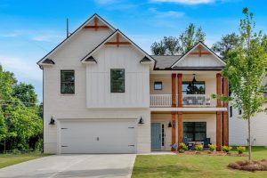 White farmhouse-style home with wood porch accents at The Overlook at Factory Shoals in Mableton, GA. 