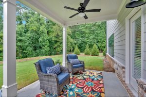 Covered back patio with wicker chairs and a ceiling fan overlooking a green yard in Dallas, GA. 